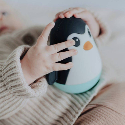 Child's hand holding a penguin-shaped toy
