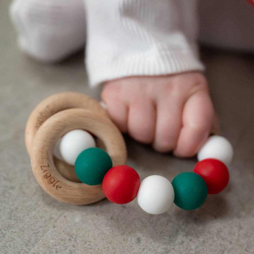 Colorful baby teething ring with wooden rings and colorful beads, held by a baby's hand.