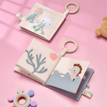 Two soft books with plush toys on a pink background