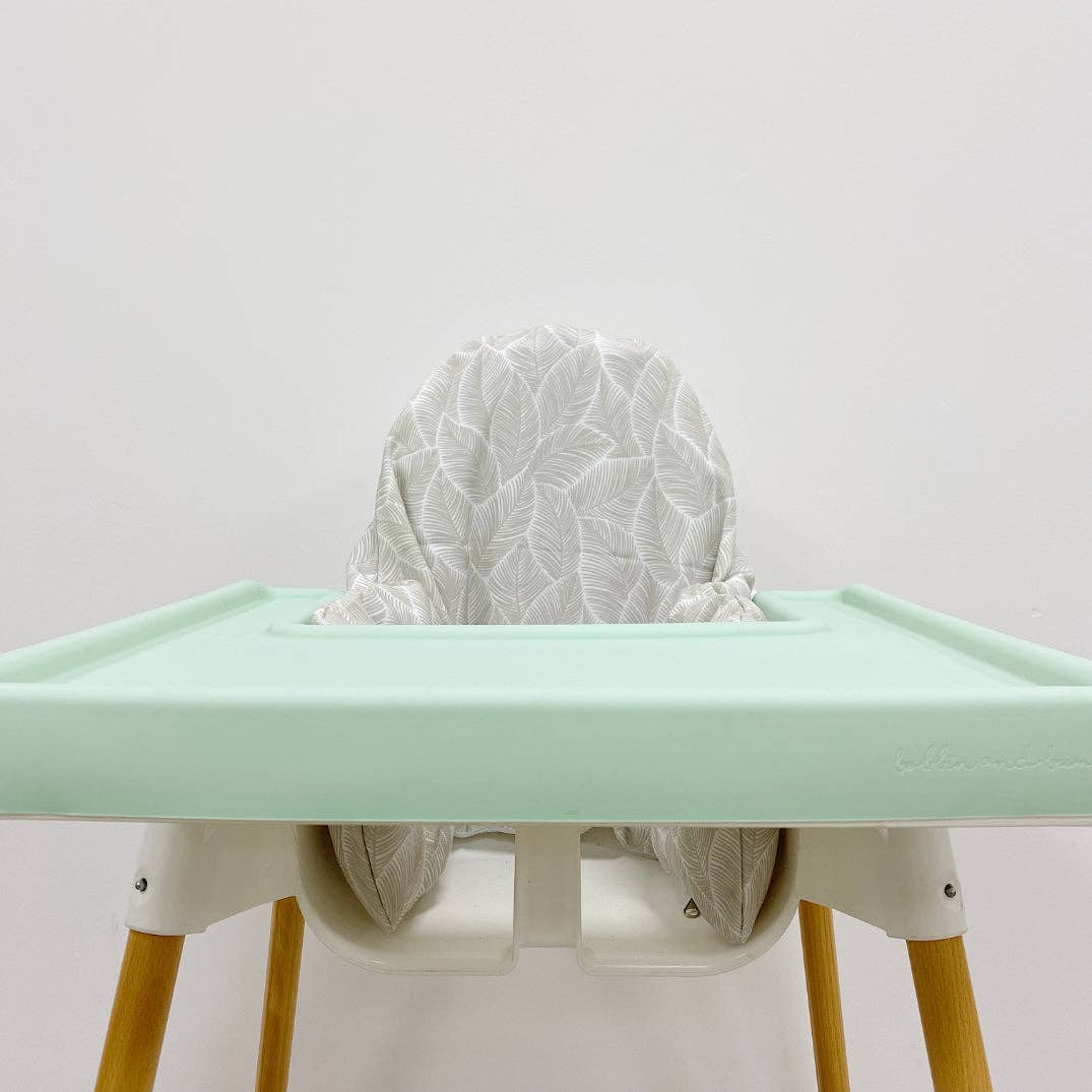 Green silicone tray cover with a white leaf pattern cushion cover on a light grey background