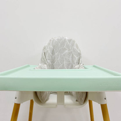 Green silicone tray cover with a white leaf pattern cushion cover on a light grey background